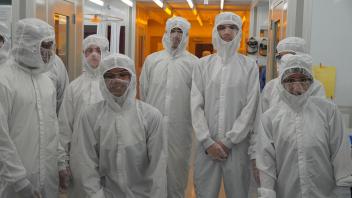 High school students in bunny suits inside the cleanroom ready to observe semiconductor fabrication processes